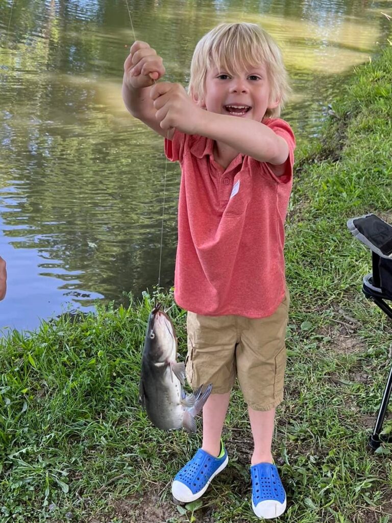 Little boy holding a fishing line with a fish on it