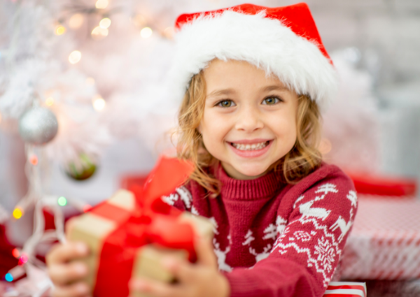 Smiling girl with Santa hat holding a gift